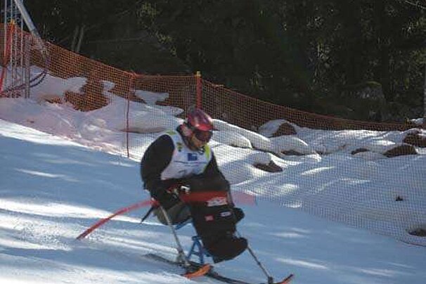 A man in a wheelchair is skiing down a snow covered slope
