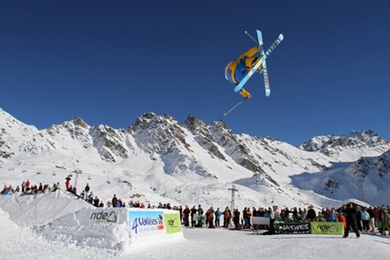 A skier is doing a trick in front of a sign that says vallees