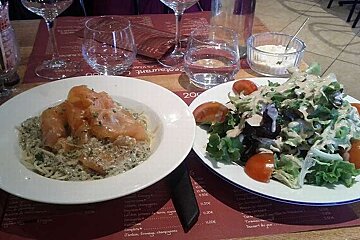 Two plates of food are on a table with a restaurant menu in the background