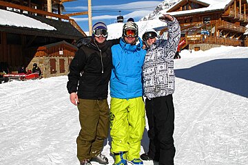 Three skiers are posing for a picture in front of a building that says ' ski club ' on it