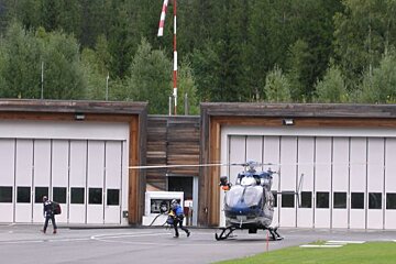 A blue and white helicopter is parked in front of a building