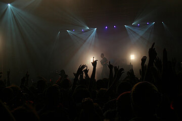 A crowd at a concert with their hands in the air
