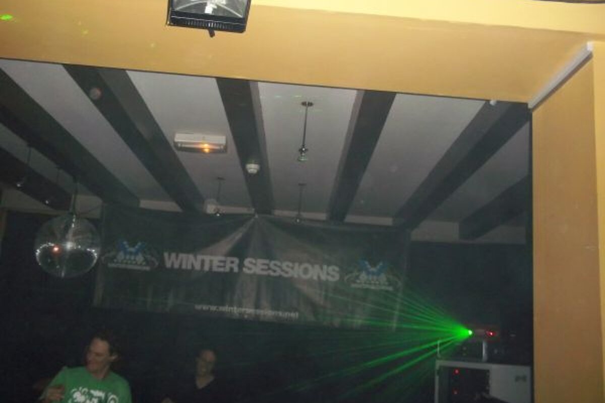 A man in a green shirt stands in front of a sign that says winter sessions