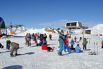 Skiers mulling around by lifts up mountain