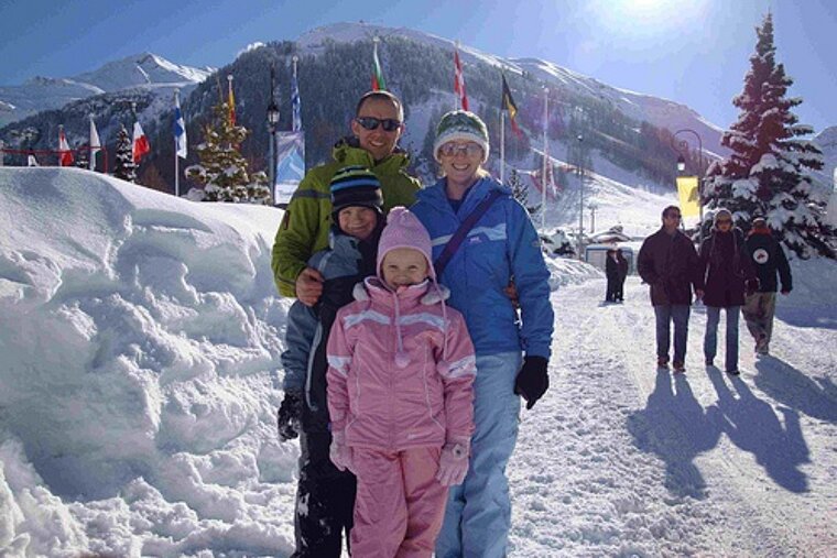 A family posing for a picture in the snow with a mountain in the background