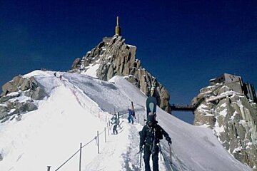 A group of skiers are going up a snowy mountain