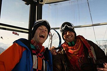 Two men are posing for a picture in a ski lift