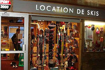 A store called location de skis has many skis on display
