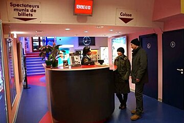 A man and woman are standing at a counter in a movie theater
