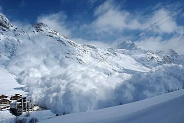 A large avalanche is coming down a snow covered mountain