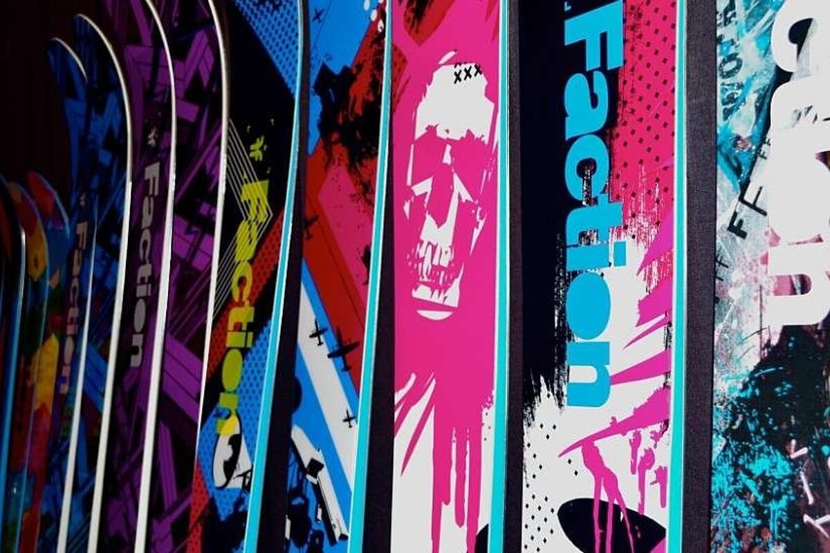 an image of a bunch of skis lined up against the wall all in different colours
