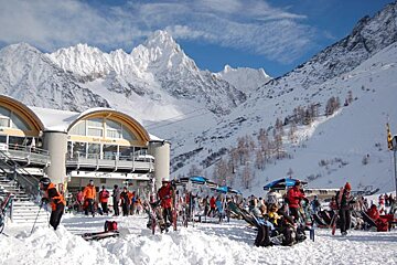 Skiers and snowboarders are gathered outside a building that says sol levante
