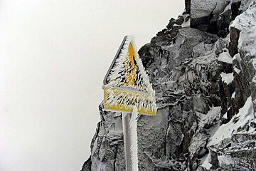A snow covered sign that says ' warning ' on it
