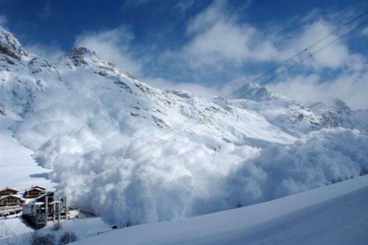 A large avalanche is coming down a snow covered mountain