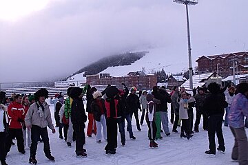 A group of people are standing on a snow covered ice rink