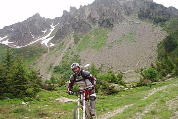 A person riding a bike on a trail with a mountain in the background