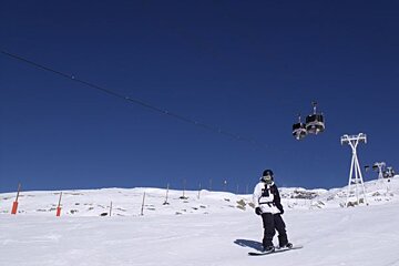 A snowboarder on a snowy slope with a ski lift in the background