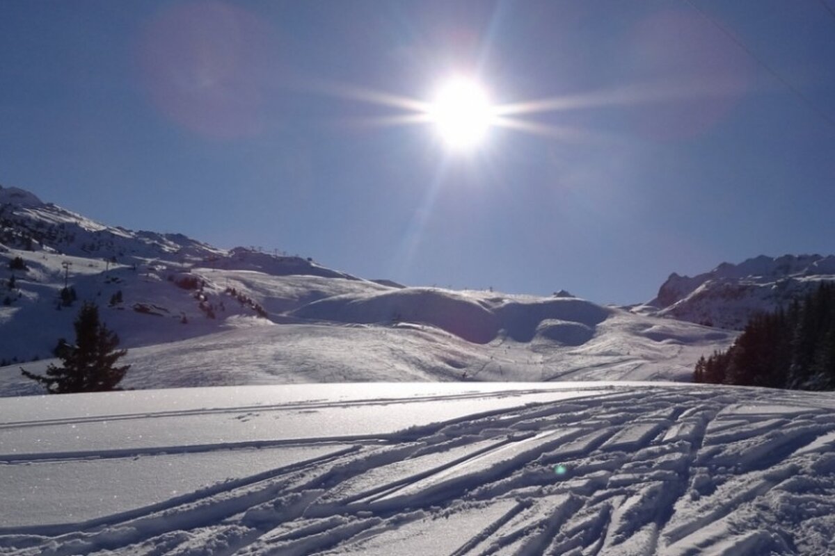 The sun is shining brightly over the snowy mountains