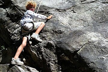 An image of a child rock climbing in the Alps, summer activity with Meribel Bureau des Guides