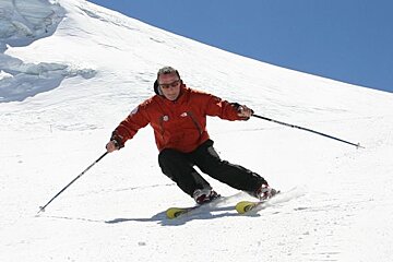 A man is skiing down a snow covered slope and his jacket says the north face