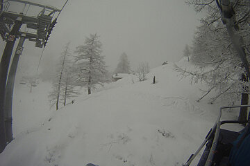 A snowboarder is riding a ski lift in the snow