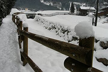 A snowy path with a wooden fence in the foreground