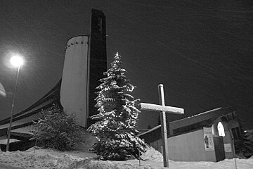 A black and white photo of a christmas tree in front of a church