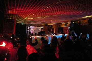 A man is playing a dj set in a dark room