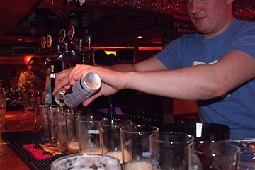 A bartender pours a can of red bull into a glass