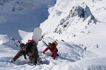 an image of 2 snow boarders clambering up a snowy mountain