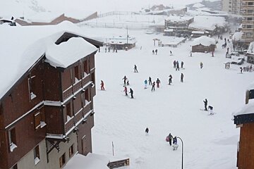 an image of skiiers and snowboarders crossing the snowy street in town