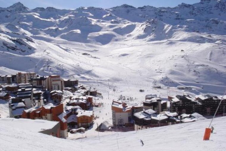 A ski resort is surrounded by snow covered mountains