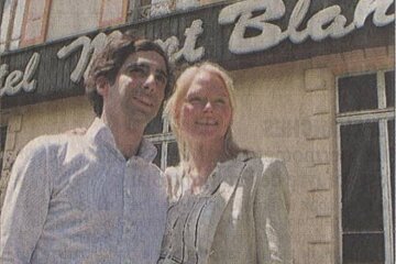 A man and woman are posing in front of a sign that says hotel mont blanc