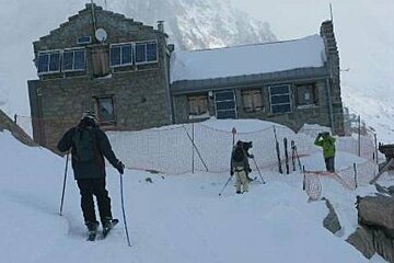 A group of people are skiing in the snow in front of a building