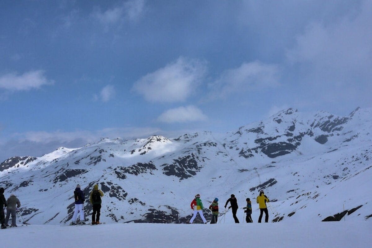 An image of skiers at the top of a run with some clouds