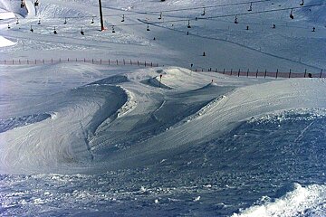A snowy ski slope with ski lifts in the background