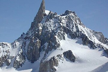 A mountain covered in snow and rocks with a blue sky in the background