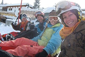 A group of people wearing ski goggles and helmets are sitting in the snow