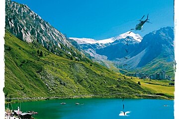 A helicopter is flying over a lake in the mountains