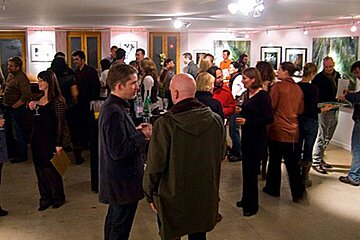 A group of people are gathered in a room with pictures on the walls