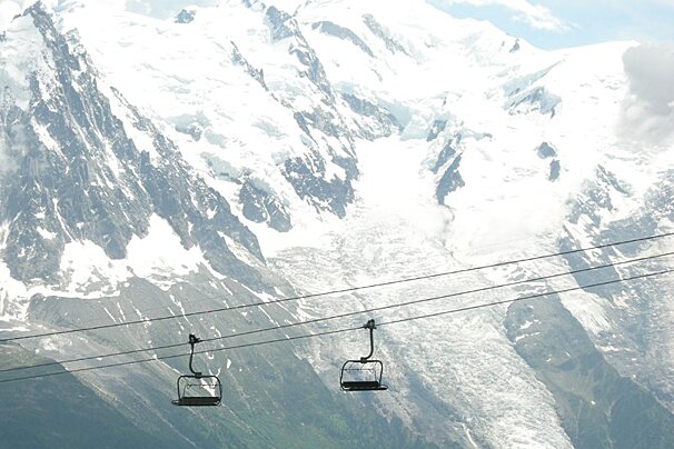 Two ski lifts are going up a snowy mountain