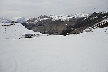 A snowy mountain landscape with a ski lift in the distance