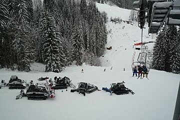 A group of people are sitting on a ski lift in the snow