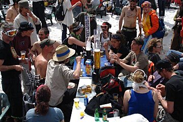 A group of people are sitting at tables in the snow drinking beer