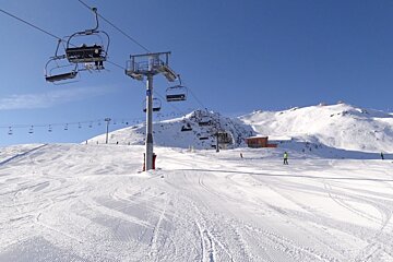 A ski lift is going up a snowy mountain