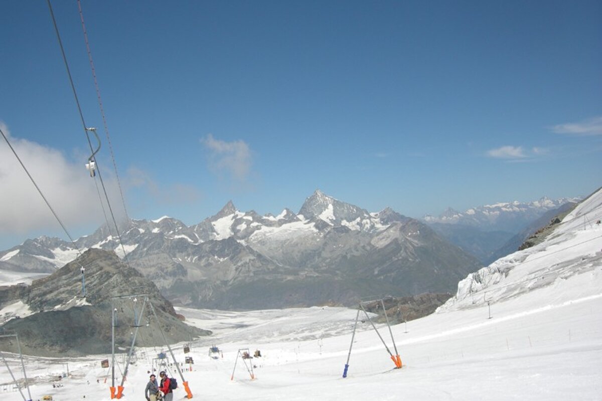 Skiers on a snowy slope with mountains in the background