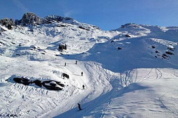 People skiing down a snowy mountain with a ski lift in the background