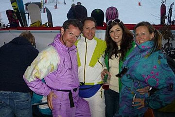 A group of people posing for a picture with a snowboard in the background that says burton