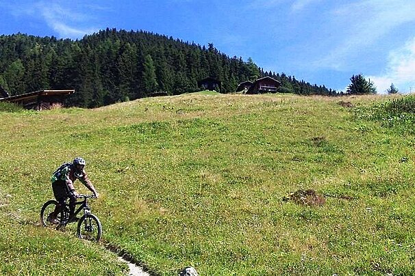 An image of a mountain biker in a summer meadow in Verbier
