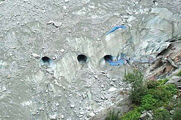 A group of people are walking through a tunnel in a glacier